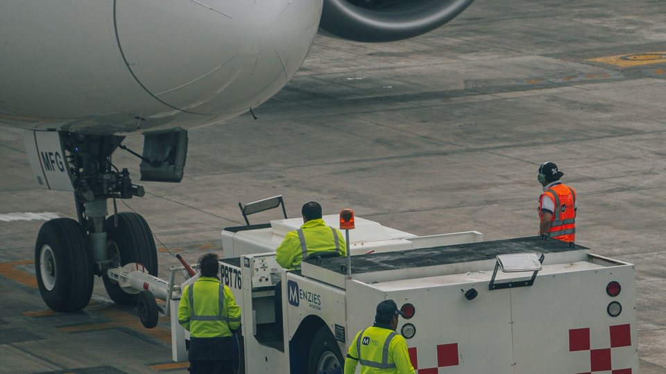 Airport ground crew working beside an aircraft and tug vehicle