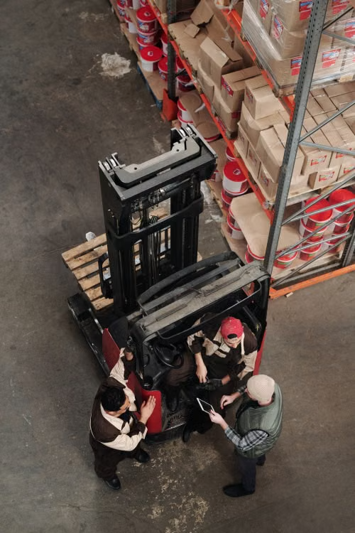 Overhead warehouse view showing a forklift and workers beside storage racks